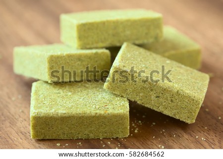 Vegetable bouillon, stock or broth cubes on wooden plate, photographed with natural light (Selective Focus on the upper edge of the right cube and one third onto the top of the left cube in the front)