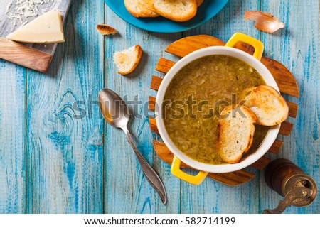 Classic onion soup with croutons. Served in yellow bowl on blue boards. Top view.