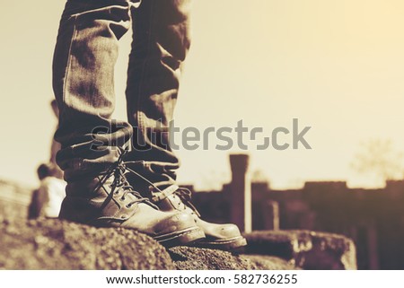 The feet of a man standing on a stone floors wearing stripey socks and leather shoes