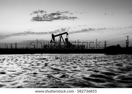 Silhouette of crude oil pump in the oilfield at sunset 