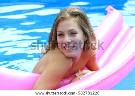 Young woman has fun with an air mattress in swimming pool