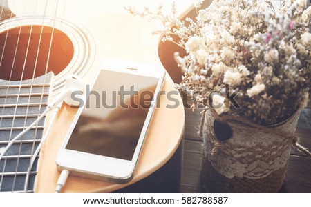 smartphone on the guitar, vintage style. can be used for ad.