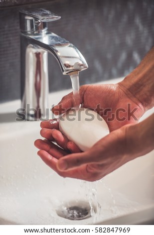 Cropped image of handsome Afro American man washing his hands in bathroom