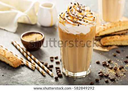 Iced caramel latte coffee in a tall glass with syrup and whipped cream. Royalty-Free Stock Photo #582849292