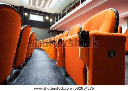in an small theater there are orange seats in a row