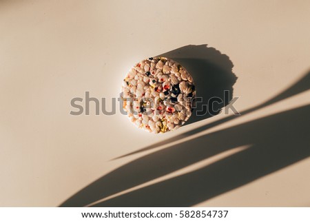 a single rice cake painted with colors on colorful white background- artistic and funny diet theme concept
