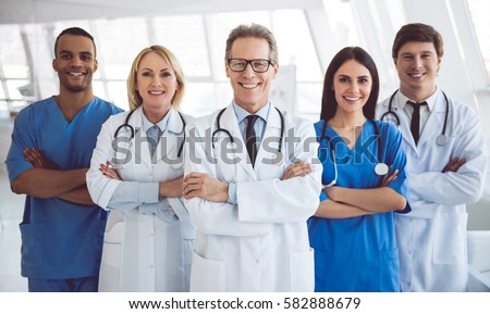 Successful team of medical doctors are looking at camera and smiling while standing in hospital Royalty-Free Stock Photo #582888679