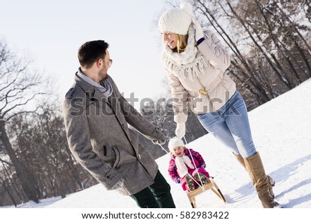 Young Parents Sledding with Kid And Enjoying On Sunny Winter Day.