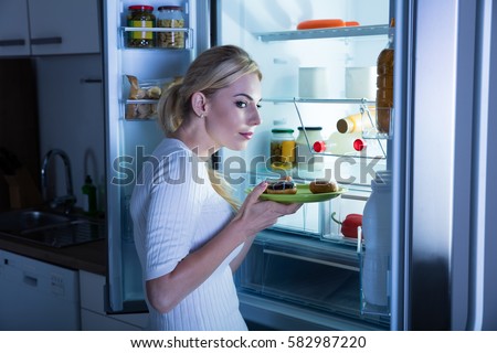 Suspicious Woman Taking Sweet Food Secretly From Fridge In The Kitchen Royalty-Free Stock Photo #582987220