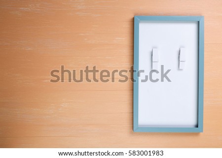 Blank photo frame with wooden pins on orange wood background. Painted scraped wooden planks texture or pattern.