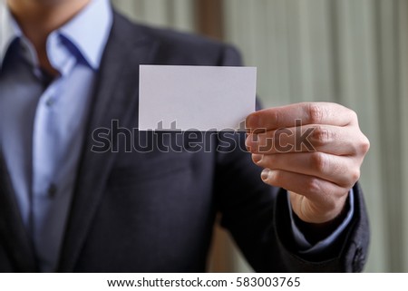 Businessman holding visit card. Man showing blank business card. Person in black suit. Mock up design.