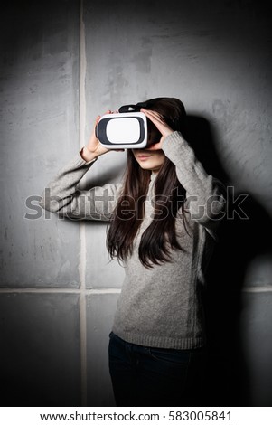 Young girl playing mobile game on virtual reality headset. Modern VR box for mobile gaming. 3d glasses technology for gamers. Play cool new mobile video games in augmented reality