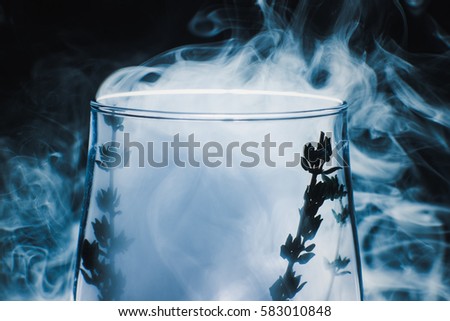 smoky wine glass with rosemary at abstract colorful smoke smooth background