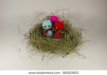 The nest of hay, dry grass knitted colorful cat, a kitten with a ribbon. A family. Handmade. Toy