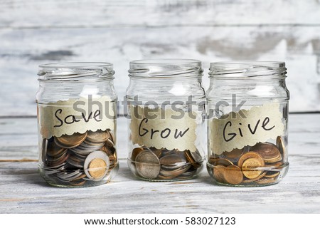 Three glass containers with coins. Idea of spending money. Royalty-Free Stock Photo #583027123