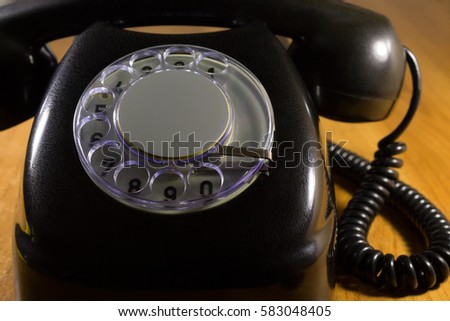 Old dial telephone in black close-up on wood background