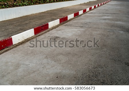 Concrete block sidewalk with Red and white concrete curb