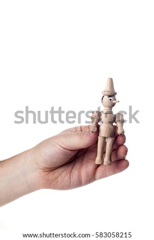 Man's hand holding a wooden Pinocchio doll.