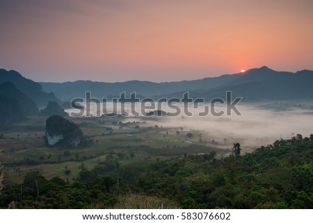 Beautiful landscape of foggy valley with a sunrise background. Photo of sunlight streaming over the foggy mountain.