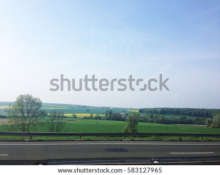 Asphalt road and green field