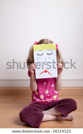 Little blonde girls holding sad face mask