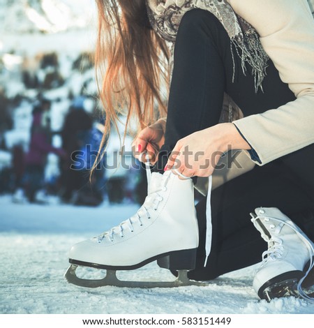 Closeup woman tie shoelaces at figure skates at ice rink close-up, ice skating