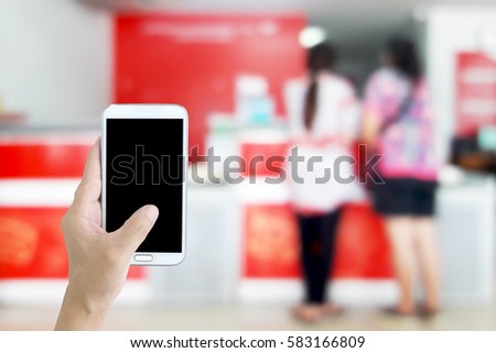 Man using a mobile phone, blur image of counter services as background.