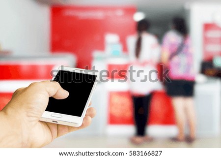 Man uses mobile phone, blur image of counter services as background.