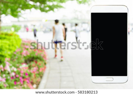 Mobile phone with blurred image of people exercising in the park as background.