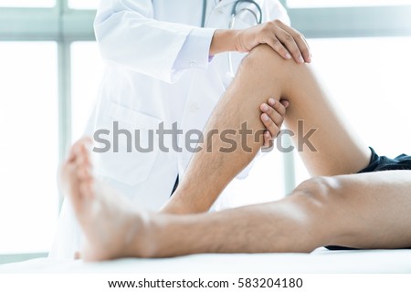 Close-up of male physiotherapist massaging the leg of patient in a physio room. Royalty-Free Stock Photo #583204180