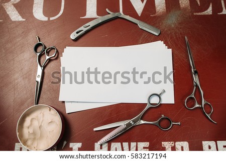 Blank card in barber tools frame free space. Empty paper with scissors, razor and cream on red table, flat lay. Barbershop, shaving, manhood concept