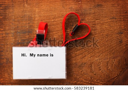 Blank ID card or security pass with red neck strap forming a shape of a heart, on rustic wooden background. WIth the word "My name is"  on the card.