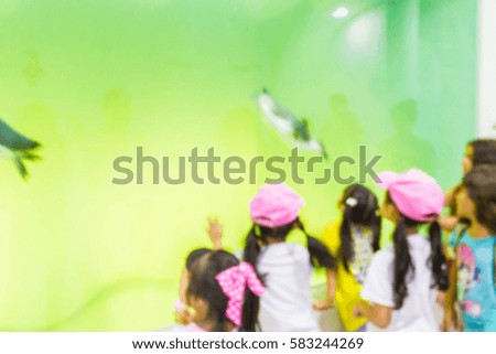 Blur image of children look at penguins in a zoo, use for background.