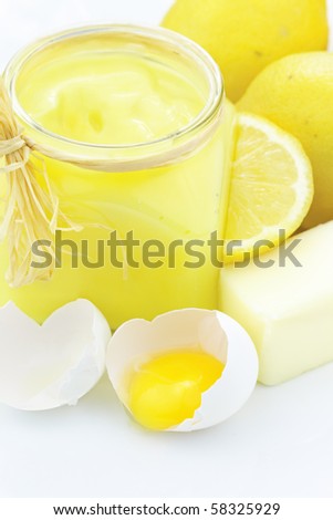 Ingredients for lemon curd with a glass jar of lemon curd ready to serve.