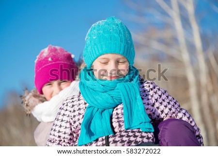 Two cute girls riding sled and having fun