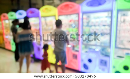 Blurry scene of People and kid playing Cabinet of claw game as abstract background - Urban and city lifestyle concept 