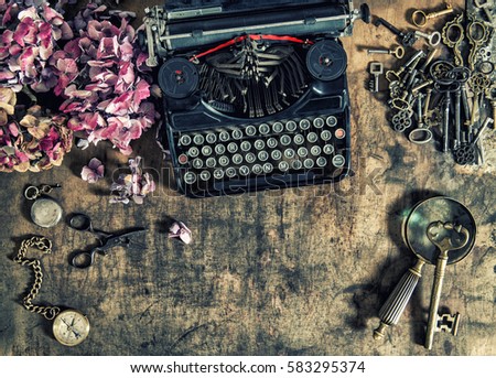 Antique typewriter, hortensia flowers and old keys on wooden table. Vintage style toned picture
