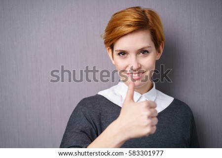 Close-up portrait of pretty young woman with short red hair showing thumbs up gesture standing against purple background with copy space