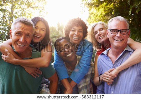 Mature Friends Giving Piggybacks In Backyard Together Royalty-Free Stock Photo #583312117