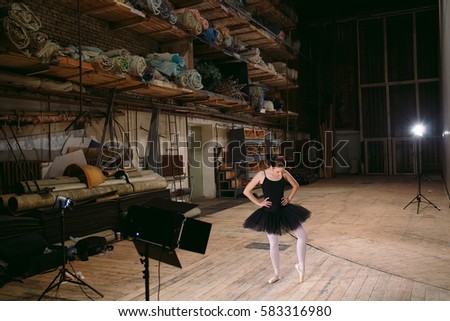 Young ballerina in black dress trains behind the scenes.