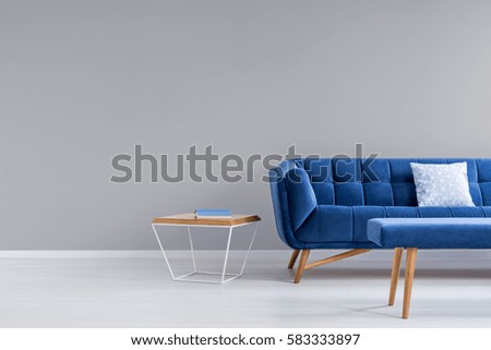 Grey room with blue couch, bench and side table Royalty-Free Stock Photo #583333897