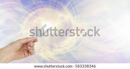 If you could see the sound waves make by an Angel Tuning Fork - female hand holding a short aluminum tuning fork on a graphic depiction of angelic sound waves background