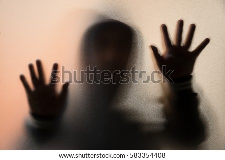 Shadow blur of horror man in jacket with hood.Hands on the glass.Dangerous man behind the frosted glass.Mystery man.Halloween background.Blur picture