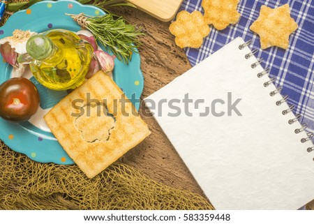 Olive oil, bread, tomatoes, rosemary, garlic and  blank recipe book  on old wooden table with copy space