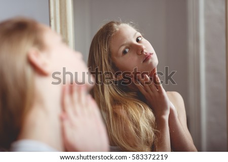 Teenage girl checking her face and body in the mirror Royalty-Free Stock Photo #583372219