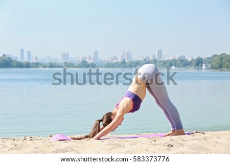 Attractive young woman doing yoga by the river