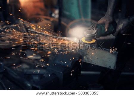 Local worker grinding,sparks during working with grinder in the old factory.Real situation picture and color toned.