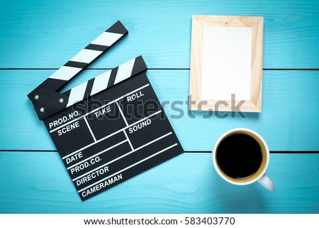 Clapper movie with blank photo frame and coffee on wooden table background.