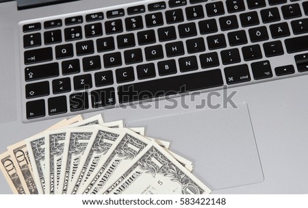 US dollars and a modern laptop. Business and online shopping concept image.