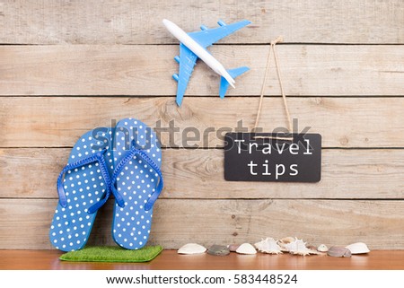 Adventure time - blackboard with text "Travel tips", plane, seashells on brown wooden background Royalty-Free Stock Photo #583448524